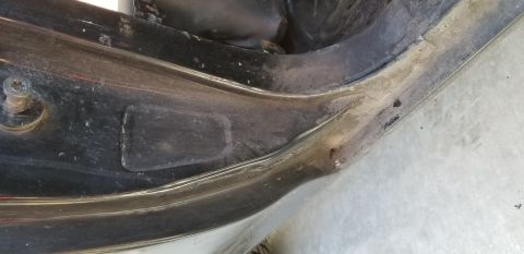 1970 Pontiac GTO — Close-up of a black car fender well with a screw and dirt.
