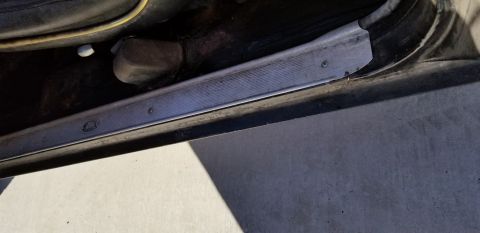 1970 Pontiac GTO — Vehicle interior door sill with metal trim and a circular emblem.