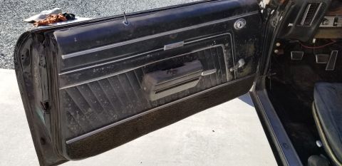 1970 Pontiac GTO — Vintage car interior with black door panel, chrome trim, and dashboard.