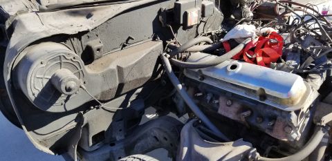 1970 Pontiac GTO - The image shows a close-up view of a V8 engine with chrome valve covers, surrounded by hoses, wiring, and other engine components. A black…