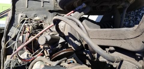 1970 Pontiac GTO - This close-up view shows the engine bay of a vintage vehicle, focusing on the power steering pump, various hoses, and electrical wiring. Th…