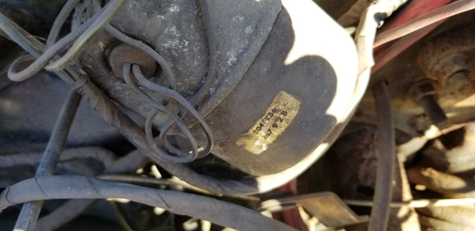 Close-up of a dusty automotive part with a label reading "04/T3S 267 9 2 B" and connected wires.