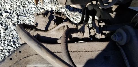 1970 Pontiac GTO - This is a close-up, low-angle shot of a dusty, gray brake caliper and associated brake lines mounted to a vehicle's suspension component. T…