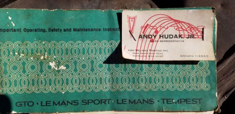 1970 Pontiac GTO - A close-up of a vintage Pontiac operating manual cover, featuring a business card for Andy Hudak Jr. of Lou Meliska Pontiac Inc. The manual…