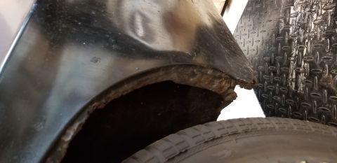 1970 Pontiac GTO - This is a close-up shot of the rusted wheel well area of a vehicle, showing significant corrosion along the fender lip. A portion of the ti…