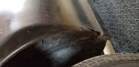 1970 Pontiac GTO - This is a close-up shot of the wheel well area of a dark-colored vehicle, showing rust and damage to the fender and inner fender liner. A t…