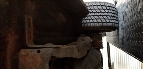 1970 Pontiac GTO - A close-up, low-angle view of the underside of a vehicle, showing rusted metal components and a tire pressed against a diamond plate surfac…