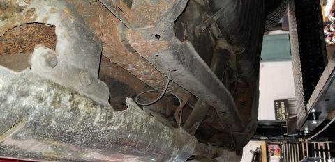 1970 Pontiac GTO - The underside of a vehicle shows significant rust on the frame and suspension components. A thin wire is visible hanging loosely near the c…