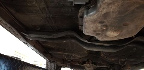 1970 Pontiac GTO - View beneath a vehicle showing the exhaust pipe routing, crossmember and dirty floor pan.