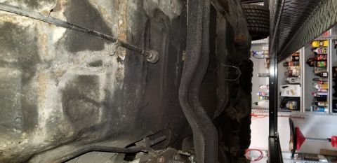 1970 Pontiac GTO - Underside view of a vehicle chassis with exhaust pipes and a brake cable visible. The chassis appears to be aged and shows signs of rust an…