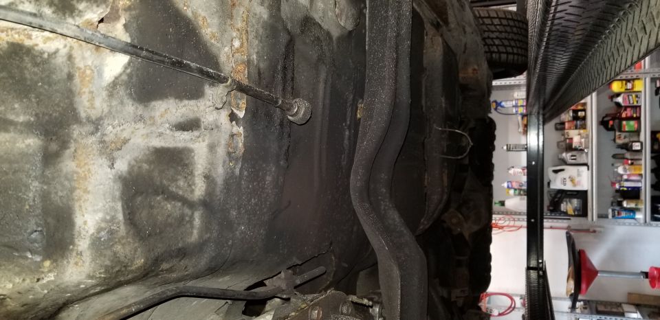 Underside of a vehicle chassis with exhaust pipes and brake cable.