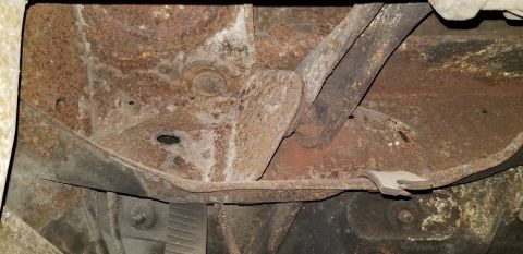 1970 Pontiac GTO - The underside of a vehicle chassis shows significant rust and corrosion on the frame and suspension components. Various metal brackets and…