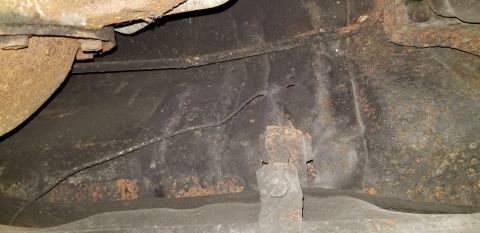 1970 Pontiac GTO - This image shows the underside of a vehicle, focusing on the rusty frame and exhaust system. The metal appears to be heavily corroded and s…