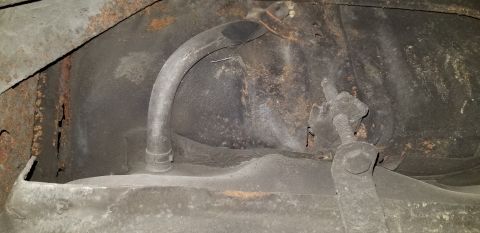 1970 Pontiac GTO - This image shows the underside of a vehicle, focusing on the fuel tank and a metal fuel line with a clamp. Rust is visible on the surroundi…