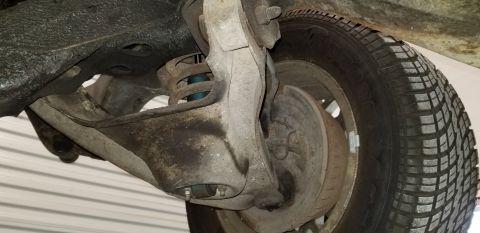 1970 Pontiac GTO - A close-up, low-angle view of the front suspension and wheel assembly of a vintage car, likely a 1970 Pontiac GTO. The image shows the shoc…