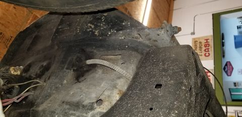 1970 Pontiac GTO - This is a close-up view of the underside of a vehicle's fender well, showing rust and grime on the metal components. A corrugated hose and…