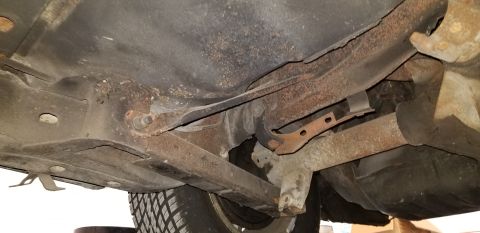 1970 Pontiac GTO - The underside of a vintage car shows significant rust and corrosion on the frame, suspension components, and exhaust system. A portion of t…