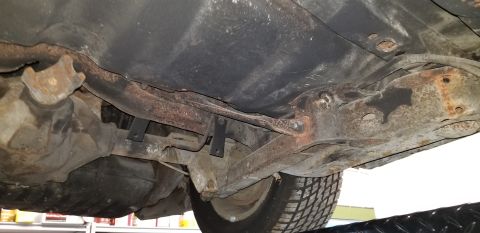 1970 Pontiac GTO - The underside of a vintage vehicle shows a rusted differential, exhaust pipe, and suspension components, including control arms and a drive…