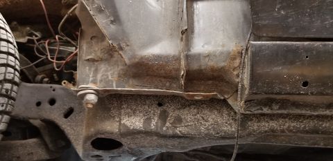 1970 Pontiac GTO - This is a close-up view of the rusted undercarriage of a vehicle, likely a classic car, showing structural metal components and some wiring.