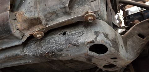 1970 Pontiac GTO - The underside of a vehicle's frame shows significant rust and corrosion, with two bolts visible holding a bracket in place.
