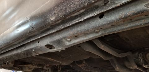 1970 Pontiac GTO - The underside of a vehicle shows a heavily rusted frame rail and body panels. Various bolts and structural components are visible, along wi…