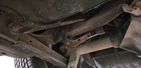 1970 Pontiac GTO - The underside of a vehicle shows rusted suspension components, including control arms and a portion of the exhaust system. A tire is visibl…
