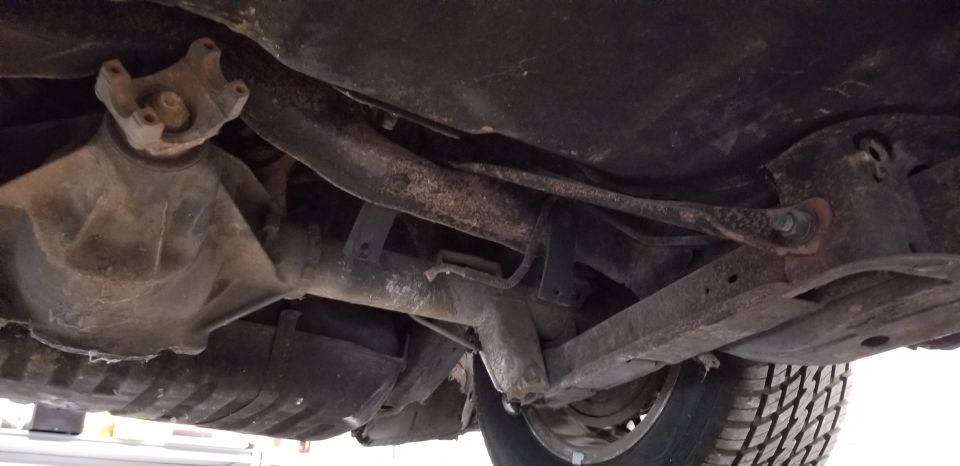 Underside of a vehicle showing rear differential, driveshaft, and suspension.