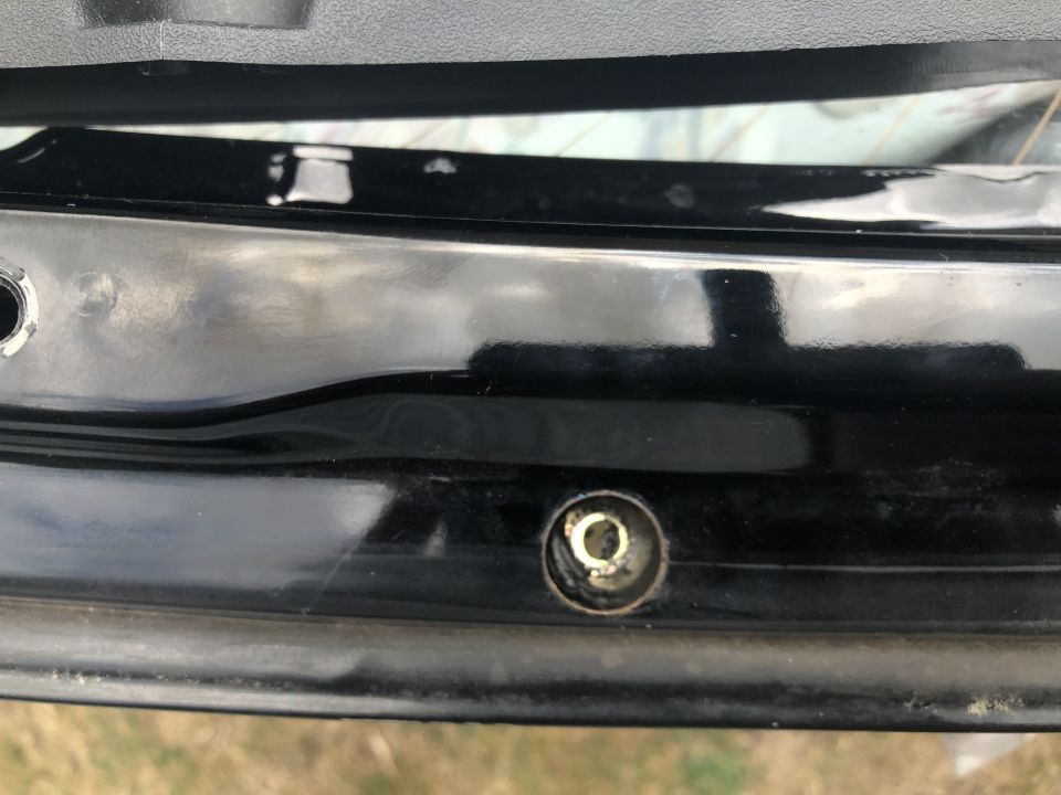 Close-up of a car's rear hatch latch mechanism with visible screw and surrounding black trim