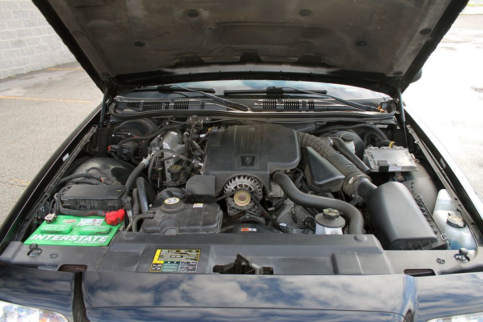 2003 Ford Crown Victoria engine bay with hood open, showing V8 engine, battery, and air intake