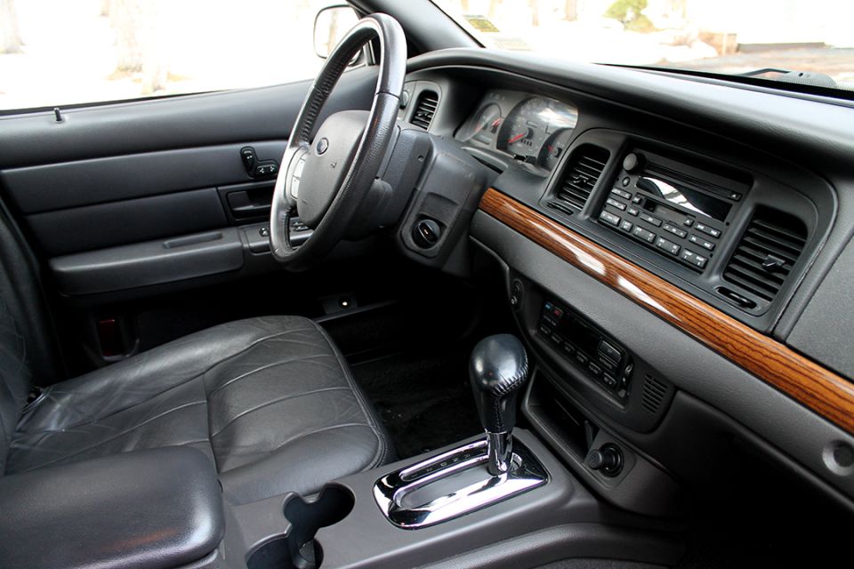 Gray leather interior of a Ford sedan with woodgrain dash trim and column shifter