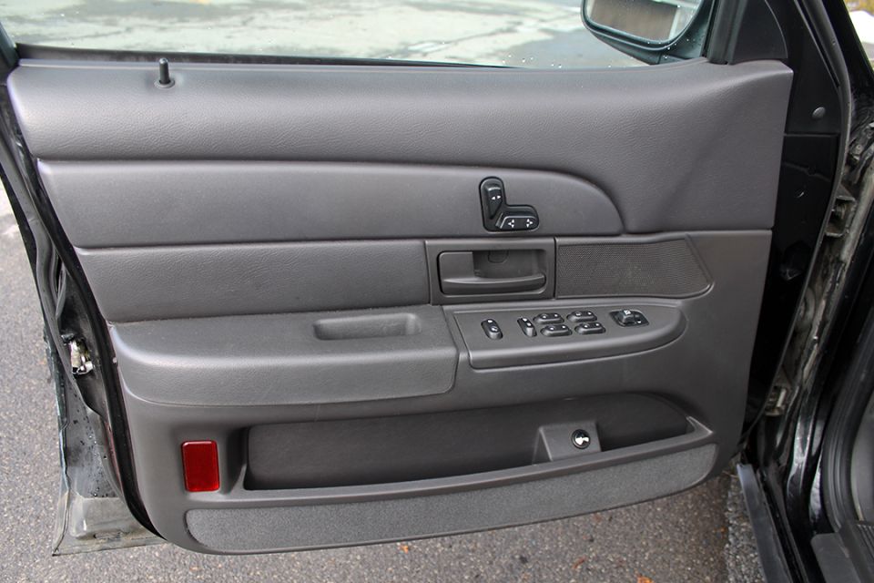 Interior of a car door showing the armrest, window controls, and door handle