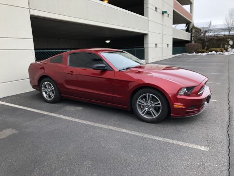 2014 Ford Mustang - Side view of a red 2014 Ford Mustang coupe parked in a lot.