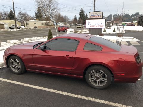 2014 Ford Mustang - A red coupe is parked in a lot with snow on the ground and a sign for Silverlake Automotive in the background.