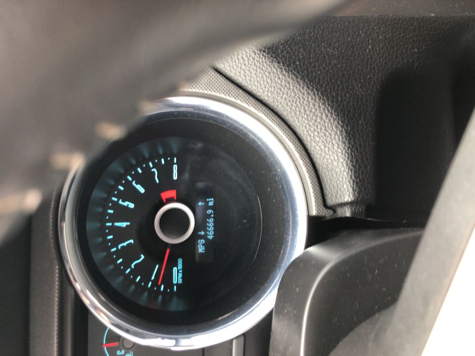 Car dashboard with a circular speedometer and odometer showing 46666.9 miles