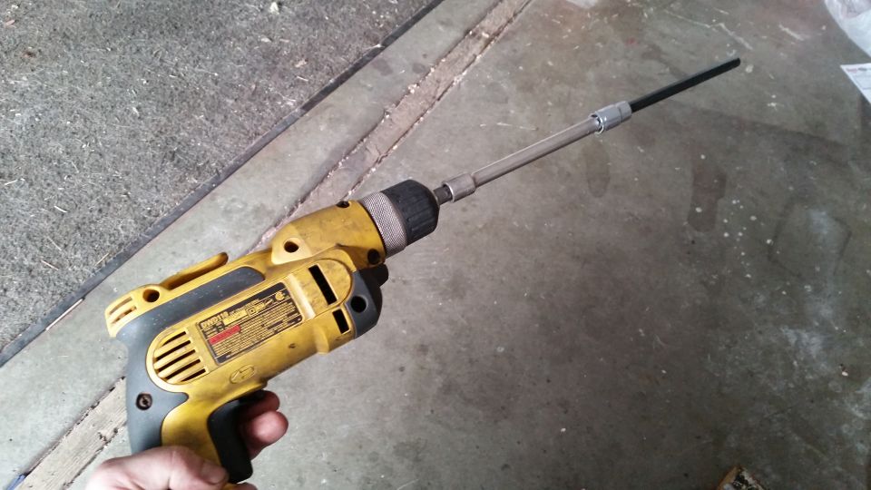 Yellow and black cordless drill with a long extension bit attached