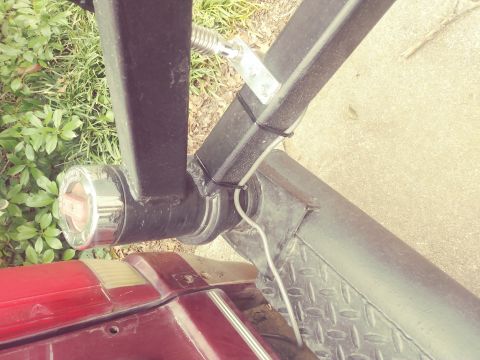 1996 Ford Bronco - Close-up view of a trailer hitch assembly connected to the rear of a red vehicle, showing the taillight detail.