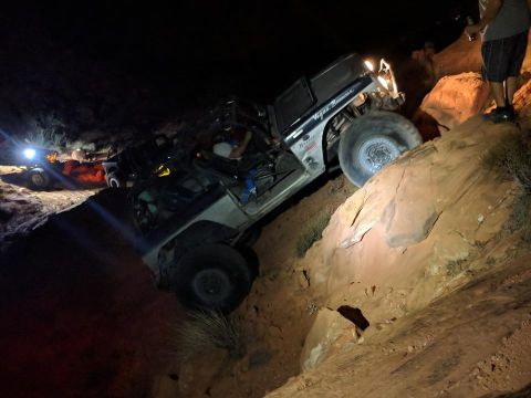 1979 Ford Bronco - An off-road vehicle navigates a challenging rocky terrain in the dark, with another vehicle visible in the background.
