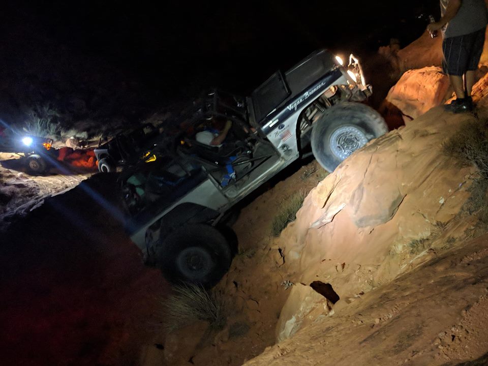 Modified off-road vehicle climbing a steep, rocky incline at night