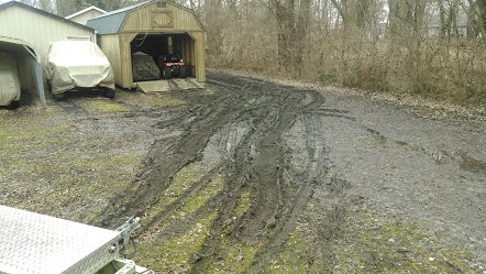 1978 Ford Bronco - A muddy driveway leads to a shed and a covered vehicle, with tire tracks indicating difficult passage.