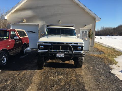 1973 Ford F-250 - A white 1973 Ford F-250 truck is parked in front of a garage with a red truck to its left.