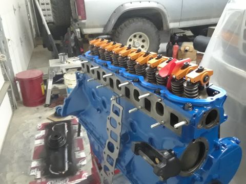 1985 Ford Bronco - Engine block assembly with visible rocker arms, with a silver SUV in the background.