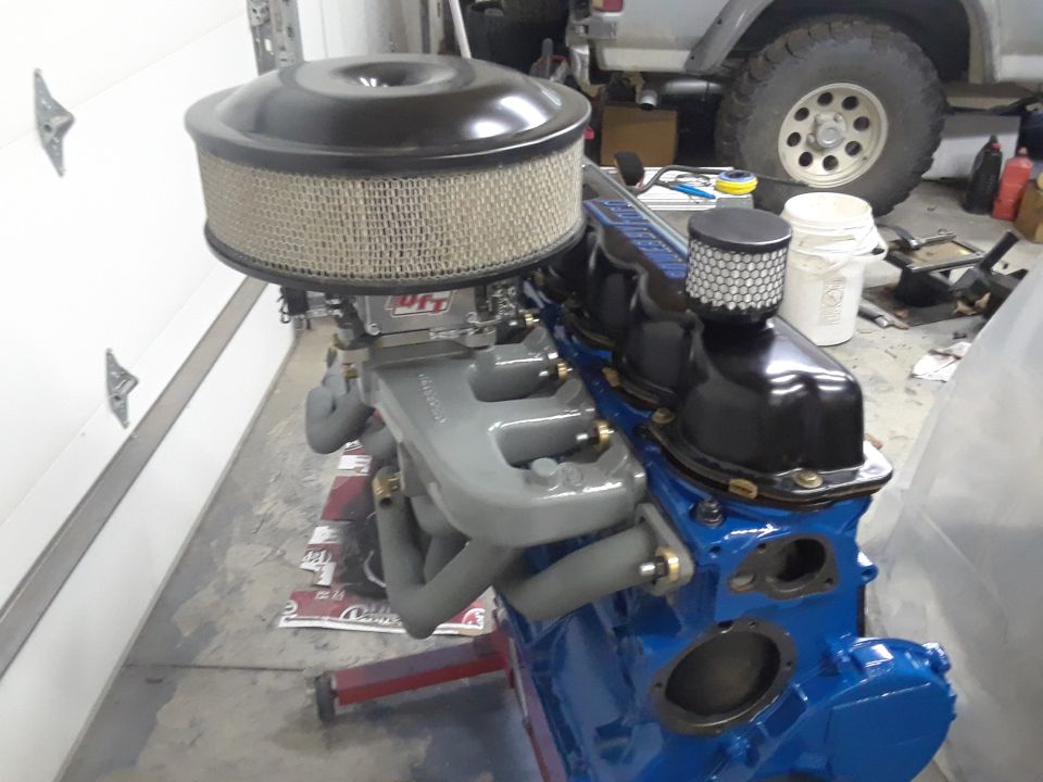Blue engine block with grey exhaust manifolds and a large air filter assembly
