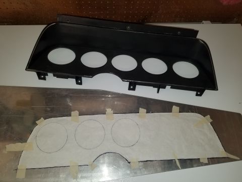 1977 Ford Ranchero - A black plastic dashboard bezel and a template for gauge cutouts are laid out on a metal surface.