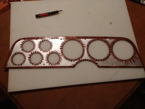 1977 Ford Ranchero - A woodgrain instrument cluster bezel is shown with a craft knife nearby, suggesting customization or repair.