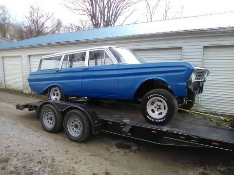 1992 Ford Bronco - A blue station wagon with a white roof is loaded onto a trailer, ready for transport.