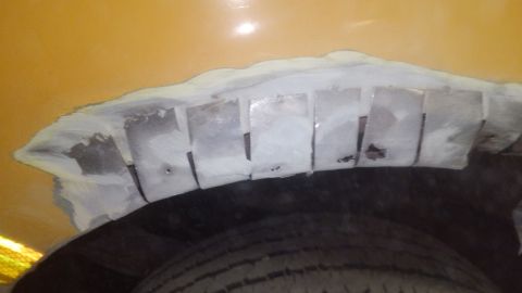 1996 Ford Bronco - Close-up of a vehicle's wheel well undergoing repair with visible metal patches and filler.