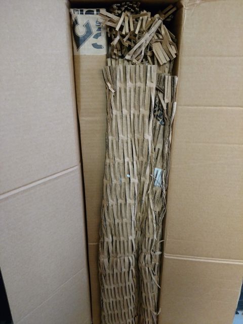 2018 Toyota 4Runner - A cardboard box contains packing materials and a long, wrapped item, suggesting a shipment of a vehicle part.