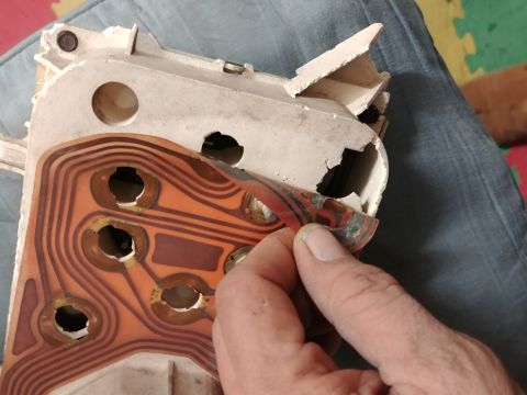 1977 Ford Ranchero - A hand peels back the circuit board from a damaged dashboard instrument cluster.