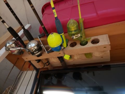 1965 Ford Mustang - Fishing gear is organized on a wooden rack, with a pink bin and a TV screen in the background.
