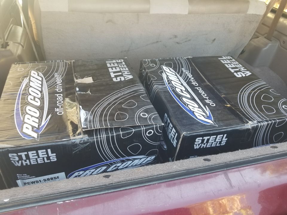 Boxes of Pro Comp steel wheels in the cargo area of a vehicle